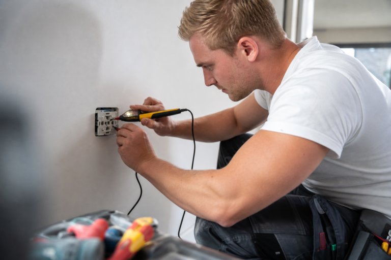 Stopcontact bijplaatsen in een muur tijdens een renovatie, met elektricien en gereedschap